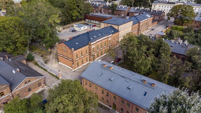 Widok na dawna szkołę powszechną wybudowana przez Karola Scheiblera przy ul. Księży Młyn 13/15, za którą znajduje się miejsce wydarzenia